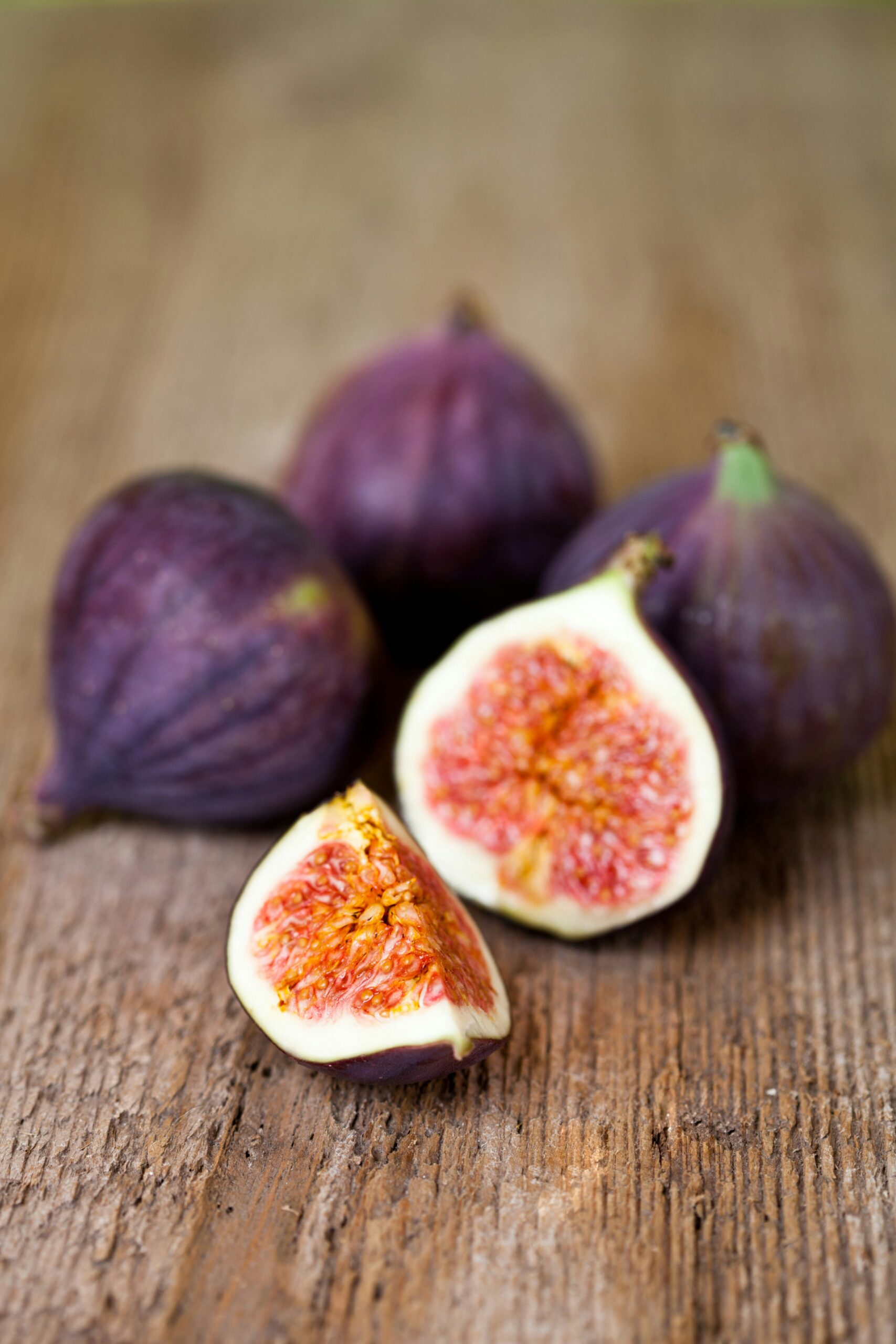 juicy-ripe-figs-fruit-tree-fertilizer-results Close-up of ripe figs, including one cut open to reveal juicy, seed-filled flesh, on a rustic wooden surface